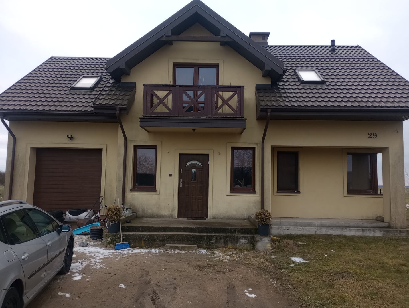 Dom jednorodzinny z lat 2000. z bezowym tynkiem i ciemnym drewnem przed modernizacja elewacji